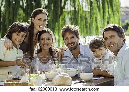 Stock Image - "Family enjoying breakfast together outdoors, group portrait". Fotosearch