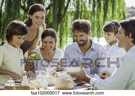 Stock Photo - Family enjoying breakfast together outdoors. Fotosearch