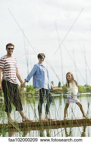 Stock Photo - "Family holding hands on dock, portrait". Fotosearch