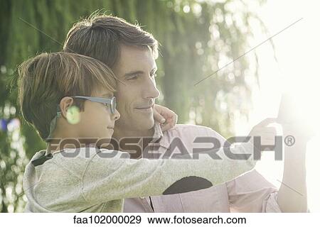 Stock Photo - "Father and son embracing outdoors, overexposure". Fotosearch