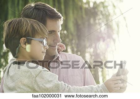 "Father and son posing for photograph with smartphone, overexposure" View Large Photo Image Stock Image - "Father and son posing for photograph with smartphone, overexposure". Fotosearch