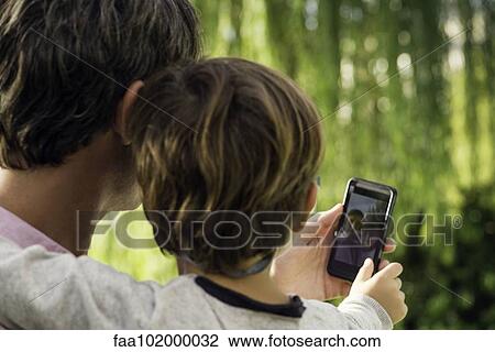 Father and son posing for photograph with smartphone View Large Photo Image Stock Image - Father and son posing for photograph with smartphone. Fotosearch