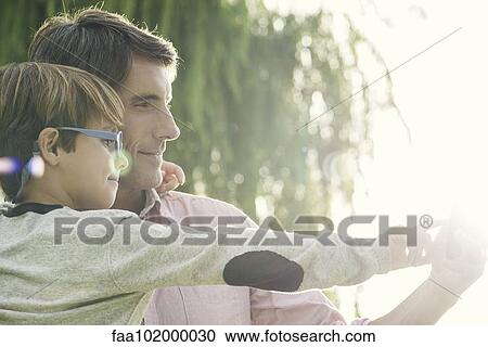 "Father and son together outdoors, overexposure" View Large Photo Image Stock Image - "Father and son together outdoors, overexposure". Fotosearch