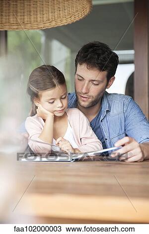 Stock Image - Father and young daughter reading together. Fotosearch