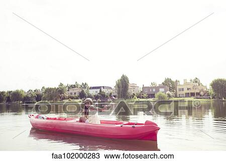 Stock Image - Girl kayaking on lake. Fotosearch