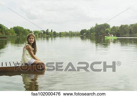 "Girl sitting on dock with feet dangling in lake, portrait" View Large Photo Image Stock Photograph - "Girl sitting on dock with feet dangling in lake, portrait". Fotosearch