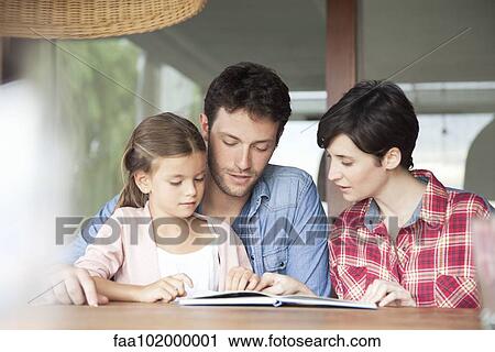 Stock Image - Little girl reading with her parents. Fotosearch
