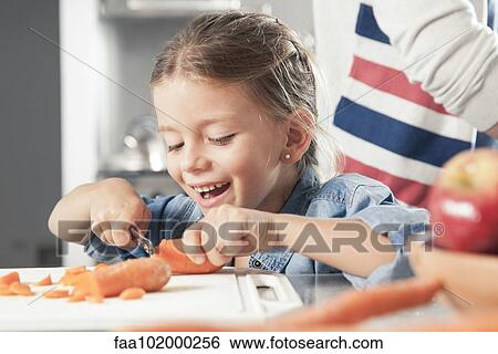 Little girl slicing carrots in kitchen View Large Photo Image Stock Photograph - Little girl slicing carrots in kitchen. Fotosearch