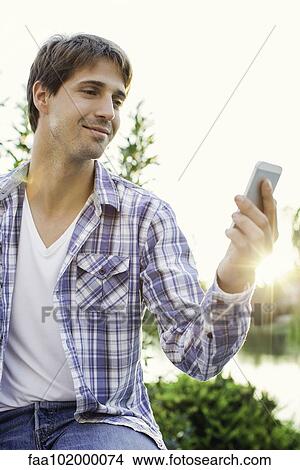 Picture - Man enjoying being outdoors and taking selfie. Fotosearch