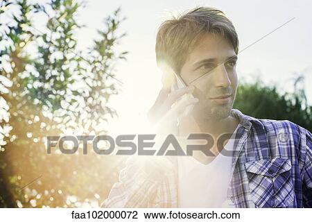 Stock Image - Man using cell phone outdoors. Fotosearch