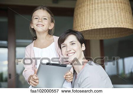 Stock Photo - Mother and daughter using digital tablet together. Fotosearch