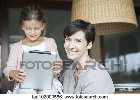 Mother and daughter using digital tablet together View Large Photo Image Stock Photograph - Mother and daughter using digital tablet together. Fotosearch
