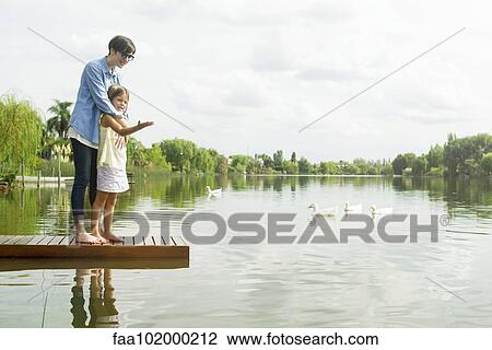 Stock Image - "Mother and young daughter standing on dock, portrait". Fotosearch
