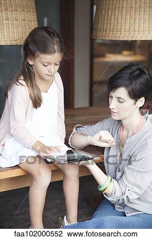 Mother and young daughter using digital tablet together View Large Photo Image Stock Image - Mother and young daughter using digital tablet together. Fotosearch