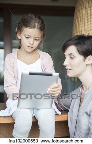 Stock Image - Mother and young daughter using digital tablet. Fotosearch