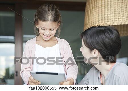 Stock Photography - Mother and young daughter using digital tablet together. Fotosearch
