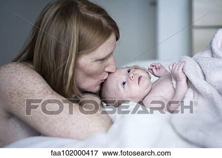 Stock Photo - Mother kissing newborn baby. Fotosearch