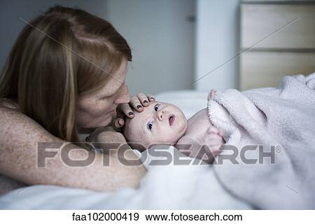 Stock Photo - Mother stroking newborn baby's head. Fotosearch