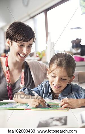 Stock Image - Mother teaching young daughter to read. Fotosearch