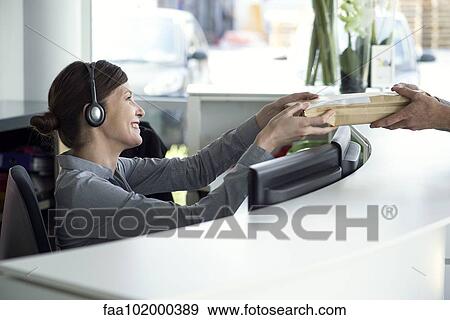 Receptionist accepting package from delivery person View Large Photo Image Stock Photo - Receptionist accepting package from delivery person. Fotosearch