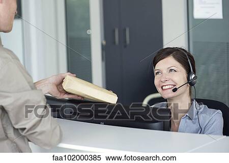 Receptionist receiving package from delivery person View Large Photo Image Stock Photography - Receptionist receiving package from delivery person. Fotosearch