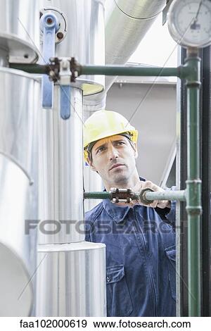 Stock Photo - Skilled worker inspecting industial equipment. Fotosearch