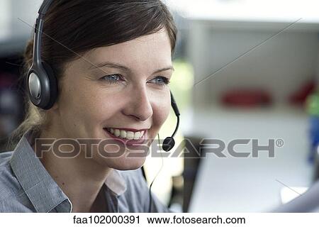 Stock Image - "Telemarketer wearing headset, smiling". Fotosearch