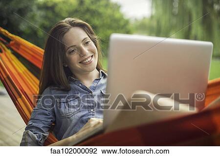 Woman reclining in hammock with laptop computer View Large Photo Image Stock Image - Woman reclining in hammock with laptop computer. Fotosearch