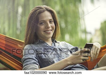 Woman reclining in hammock with smartphone View Large Photo Image Stock Image - Woman reclining in hammock with smartphone. Fotosearch