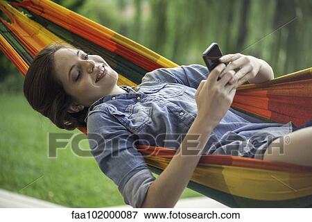 Woman relaxing in hammock with smartphone View Large Photo Image Stock Photo - Woman relaxing in hammock with smartphone. Fotosearch
