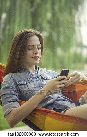 Woman relaxing in hammock with smartphone View Large Photo Image Stock Photo - Woman relaxing in hammock with smartphone. Fotosearch