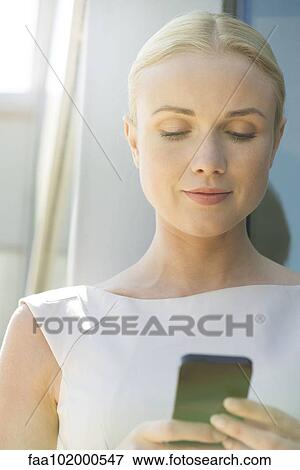 Stock Photo - Woman text messaging with smartphone. Fotosearch
