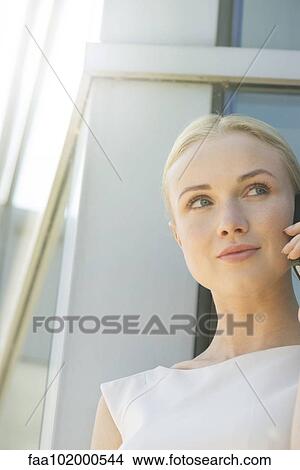 Picture - "Woman using cell phone, smiling". Fotosearch