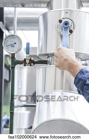 Picture - Worker adjusting control lever on industrial equipment. Fotosearch