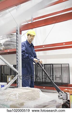Worker operating pallet jack in warehouse View Large Photo Image Stock Photo - Worker operating pallet jack in warehouse. Fotosearch