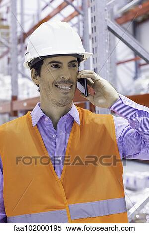 Worker using cell phone at industrial site View Large Photo Image Stock Photography - Worker using cell phone at industrial site. Fotosearch