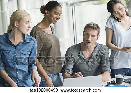 Workers gathered around desk of colleague View Large Photo Image Stock Image - Workers gathered around desk of colleague. Fotosearch