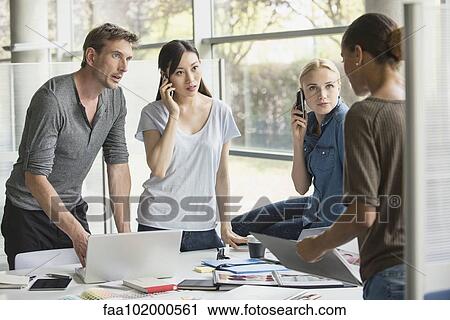 Stock Image - Workers listening to colleague share idea. Fotosearch