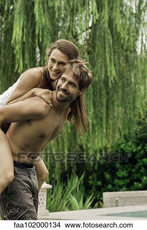 Picture - Young man giving girlfriend piggyback ride. Fotosearch