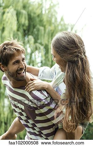 Stock Photo - Young man giving girlfriend piggyback ride. Fotosearch