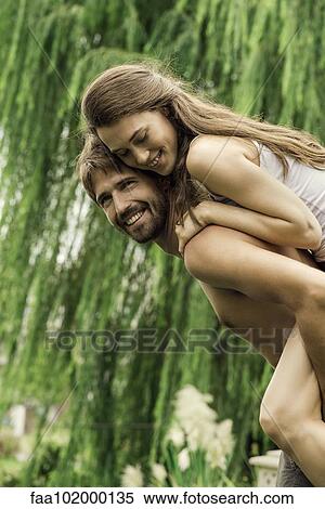 Stock Photography - Young man giving girlfriend piggyback ride. Fotosearch