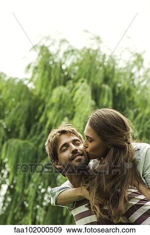 Stock Photo - Young woman kissing boyfriend. Fotosearch