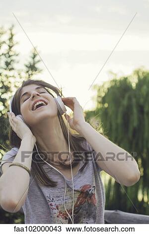 Young woman listening to music through headphones View Large Photo Image Stock Image - Young woman listening to music through headphones. Fotosearch