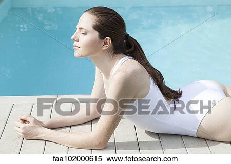 Young woman sunbathing beside pool with eyes closed View Large Photo Image Stock Photography - Young woman sunbathing beside pool with eyes closed. Fotosearch