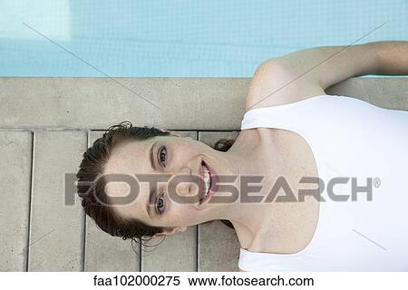 "Young woman sunbathing by pool, smiling cheerfully, portrait" View Large Photo Image Stock Photography - "Young woman sunbathing by pool, smiling cheerfully, portrait". Fotosearch