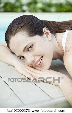 "Young woman sunbathing with head resting on hands, portrait" View Large Photo Image Stock Image - "Young woman sunbathing with head resting on hands, portrait". Fotosearch