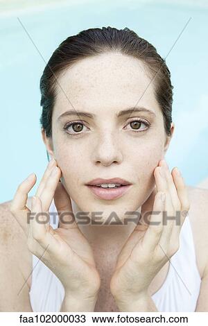 Stock Image - "Young woman touching her face, portrait". Fotosearch