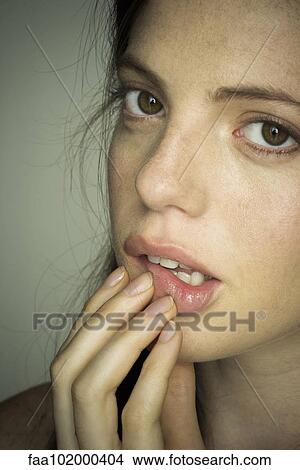 Picture - "Young woman touching lips nervously, portrait". Fotosearch