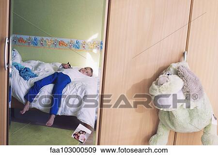 Stock Photo - "Boy daydreaming on bed, reflected in bedroom mirror". Fotosearch