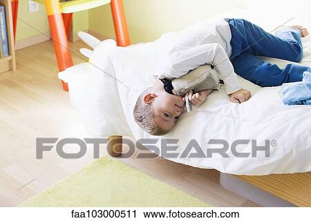 Boy lying on bed with stuffed toy View Large Photo Image Stock Image - Boy lying on bed with stuffed toy. Fotosearch